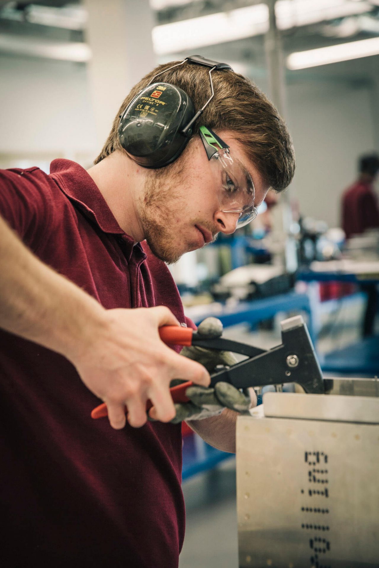 A GKN engineering student works with ear-defenders and goggles on